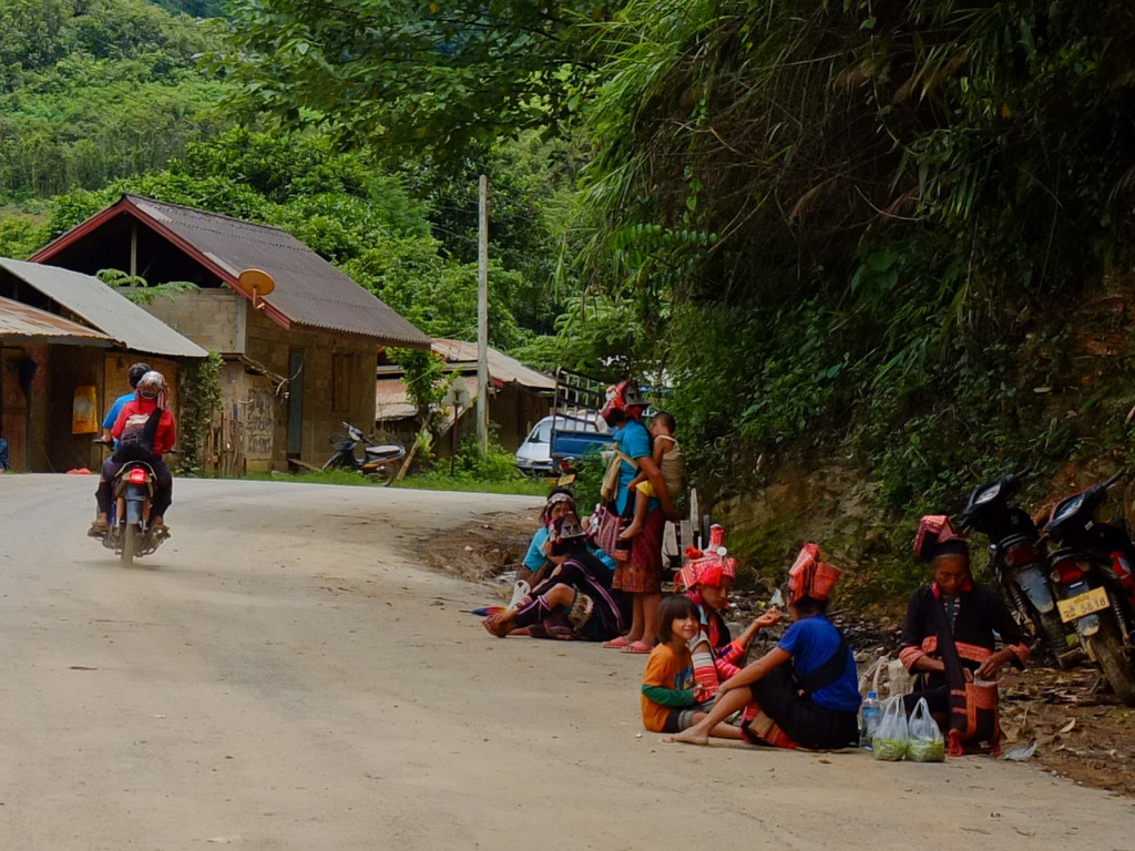 Women of the Akha tribe of amazing dresses and traditions sitting at cross roads, trying to sell their handicrafts to tourists and other people passing by.